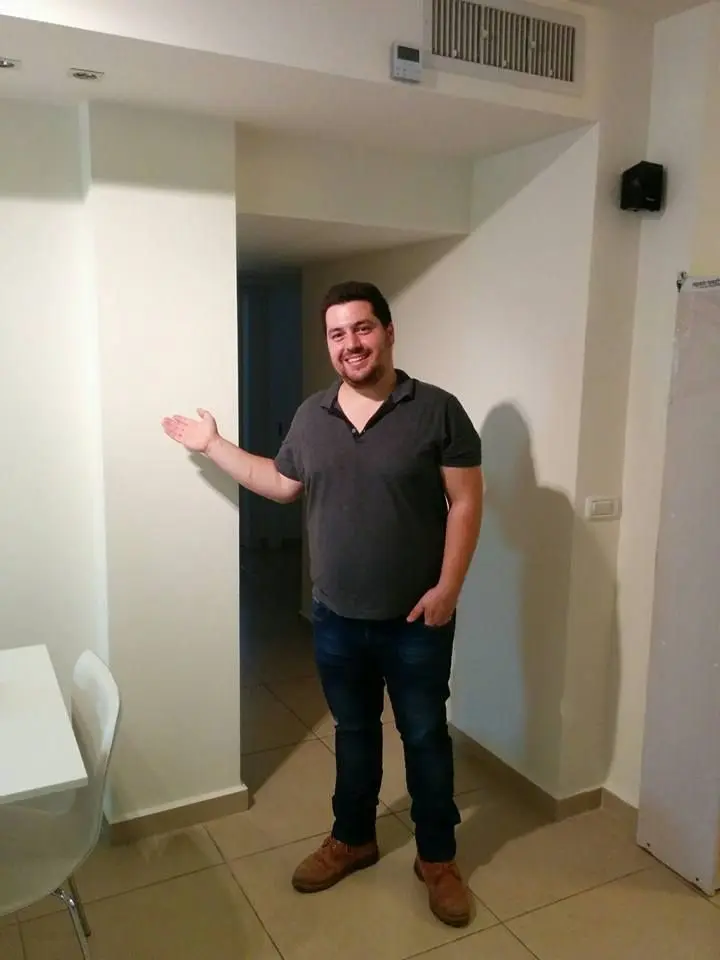 גבר מציג בחיוך מסדרון משופץ ומואר